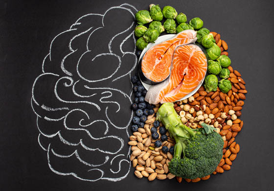 Food related to brain health (broccoli, nuts, fruit, salmon, and more) shaped like a brain; other half of the image is a line drawing of a brain