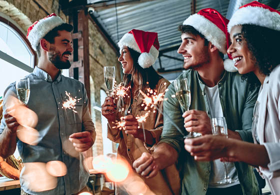 Young colleagues with Santa hats, champagne, and sparklers at the office Christmas party