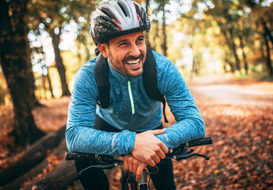 Fit, attractive man talking a minute to breathe, leaning over the handlebars of his bike 