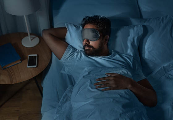 Attractive man sleeping at night with a sleep mask on his face