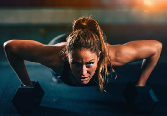 Powerful young, attractive woman doing workout on the ground with dumbbells